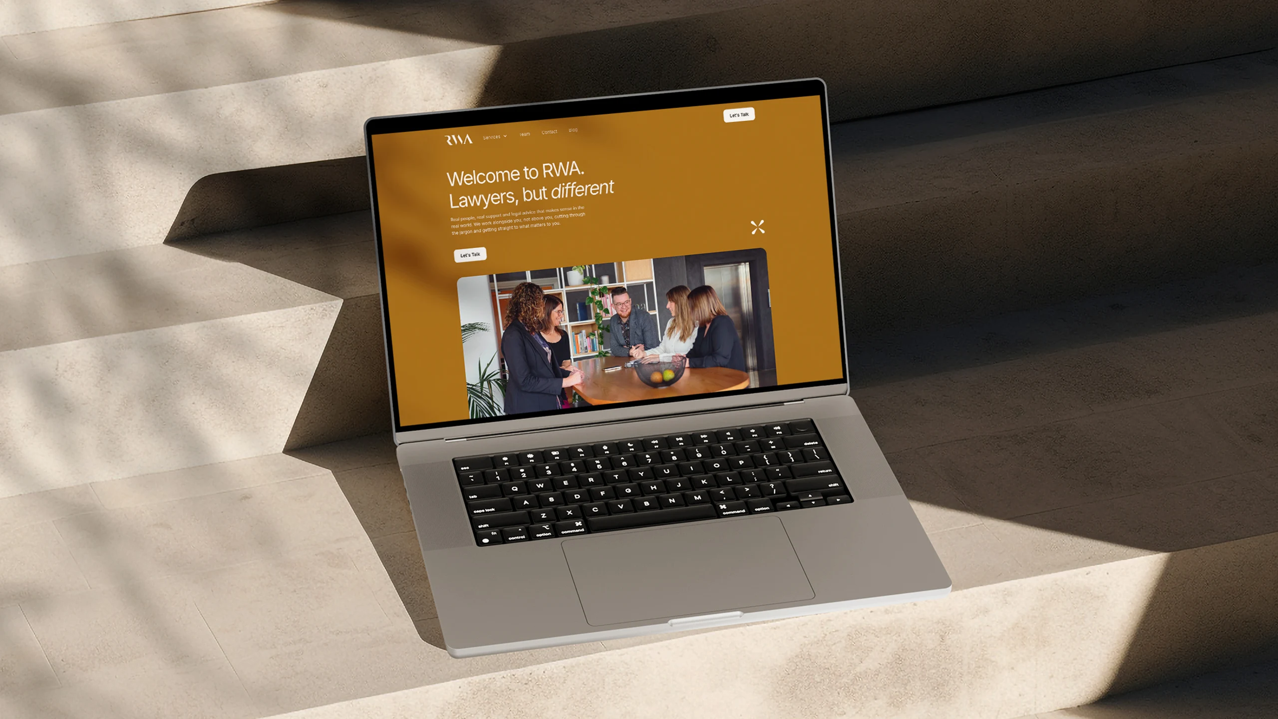 RWA lawyers branded website home page mocked up on a MacBook computer sitting on a concrete staircase with dramatic shadows